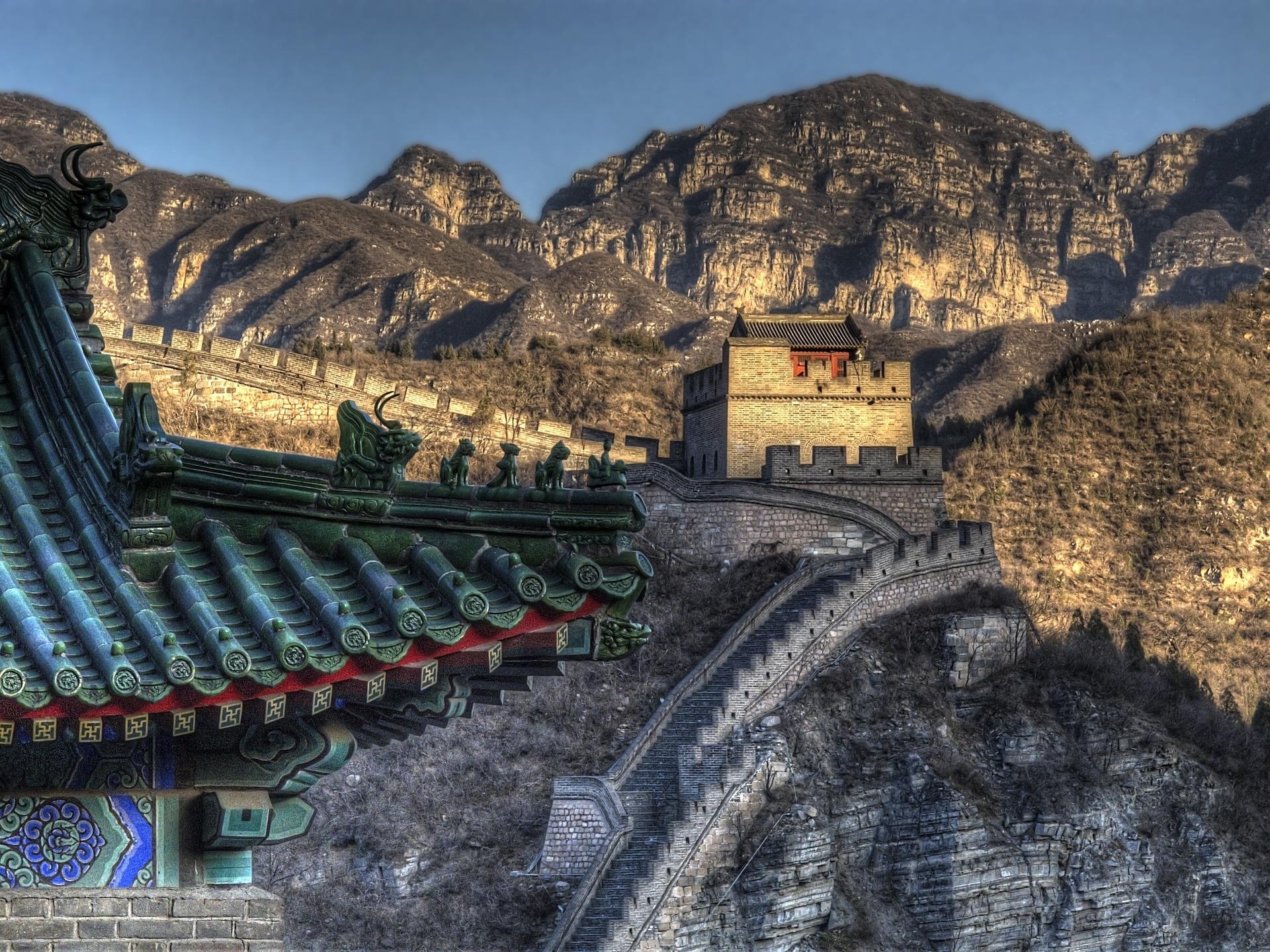 Mutianyu Great Wall section with stone watchtower and winding walls across rugged mountains under clear sky.