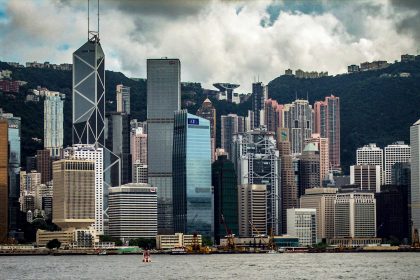 ong Kong skyline with modern skyscrapers, including Bank of China Tower, viewed across Victoria Harbour.
