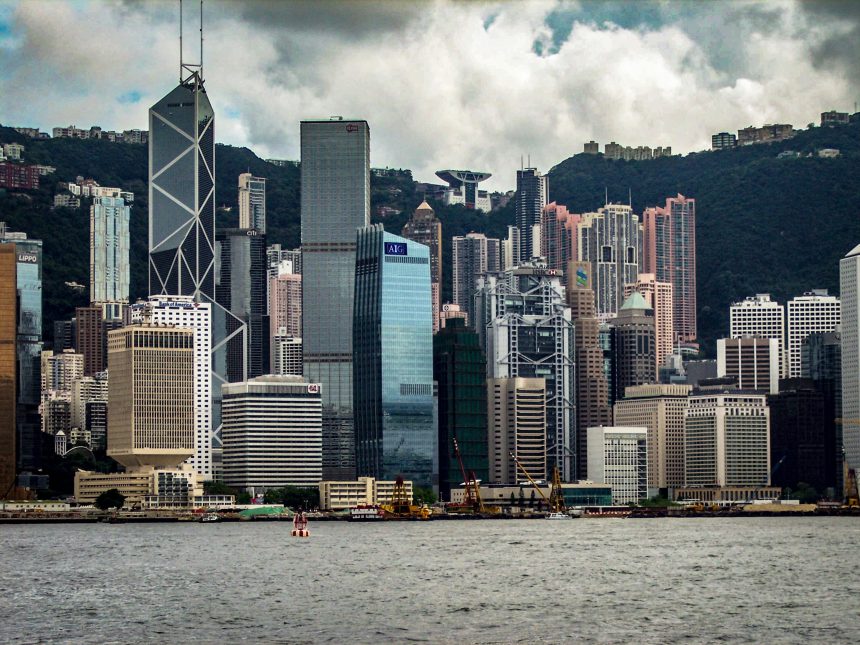 ong Kong skyline with modern skyscrapers, including Bank of China Tower, viewed across Victoria Harbour.