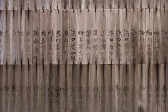 Traditional Japanese calligraphy written on vertical wooden planks, showcasing weathered wood and dark ink brush strokes.