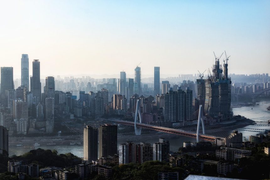 Panoramic view of Chongqing city skyline with skyscrapers, cable-stayed bridge, and the Yangtze River at sunset.